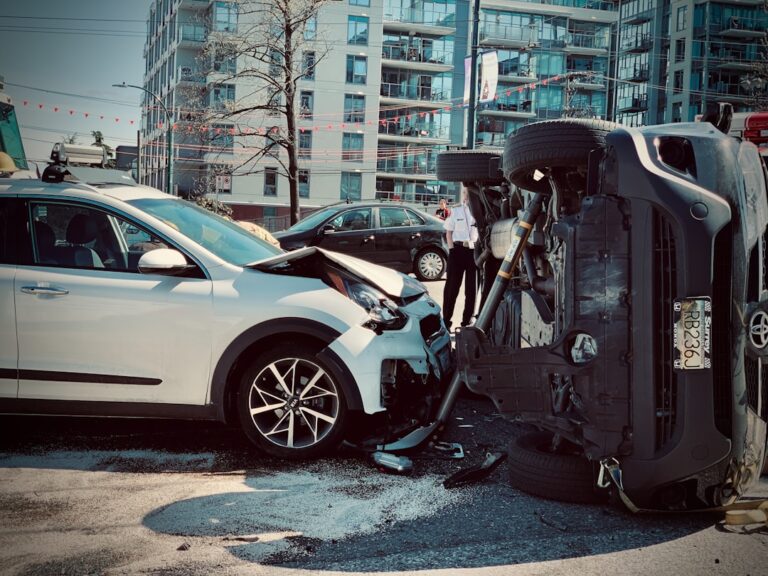 Two drivers standing beside their vehicles on a residential street, exchanging information and taking photos of minor damage.